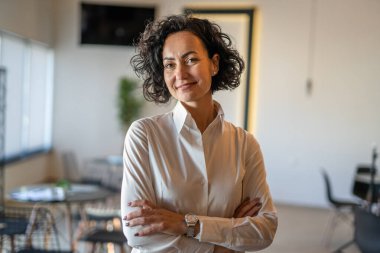 Yetişkin bir kadın Kafkas kadın iş kadını iş yerinde ya da evde duruyor gerçek insanlar yer kopyalıyor beyaz gömlek kıvırcık saçlar giyiyor