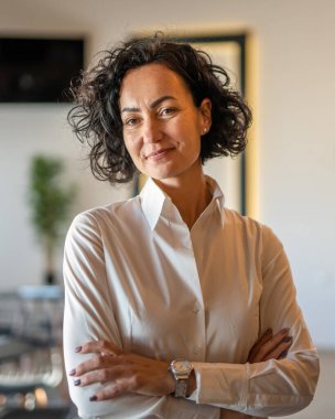 Yetişkin bir kadın Kafkas kadın iş kadını iş yerinde ya da evde duruyor gerçek insanlar yer kopyalıyor beyaz gömlek kıvırcık saçlar giyiyor