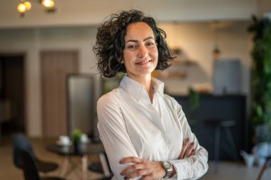 Yetişkin bir kadın Kafkas kadın iş kadını iş yerinde ya da evde duruyor gerçek insanlar yer kopyalıyor beyaz gömlek kıvırcık saçlar giyiyor