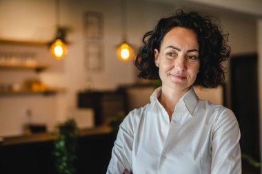 Yetişkin bir kadın Kafkas kadın iş kadını iş yerinde ya da evde duruyor gerçek insanlar yer kopyalıyor beyaz gömlek kıvırcık saçlar giyiyor