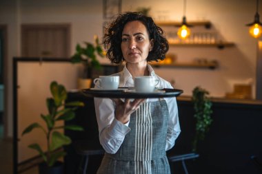 Kafe ya da lokantada çalışan olgun bir kadın garson kahve tepsisi taşıyor. İş yerindeki bayan girişimci. Gerçek insanlar uzay küçük işletme konseptini kopyalıyor.