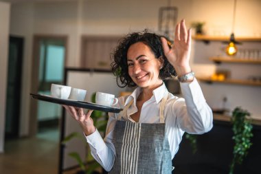 Kafe ya da lokantada çalışan olgun bir kadın garson kahve tepsisi taşıyor. İş yerindeki bayan girişimci. Gerçek insanlar uzay küçük işletme konseptini kopyalıyor.