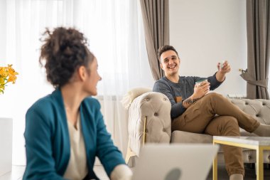 Erkek ve kadın mutlu beyaz çift evde oturup sohbet ediyor ve sohbet ediyorlar. Gerçek insanlar. Aile kavramı.