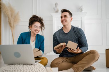Kafkasyalı genç bir çift, karı-koca, karı-koca ya da sevgili evde bilgisayarın önünde hediye kutusunu açıp internetten fotokopi çekiyorlar.