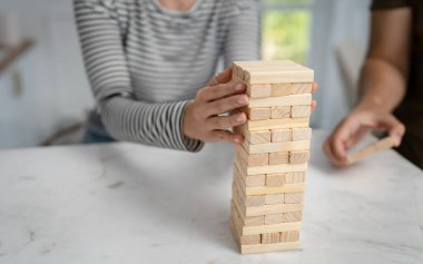 Jenga oyunu için tuğla istifleyen beyaz bir kadının elini kapatıyoruz. Tahta parçaları kuleyi kapatıyor. Uzay ailesinin oyun tahtasını kopyalıyor.