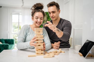Kadın ve erkek mutlu beyaz çift ya da evde Jenga masası oyunu oynayan arkadaşlar mutlu gülücükler, boş zaman geçirerek birlikte vakit geçiriyorlar aile ortamını kopyalayarak gerçek insanları kopyalıyorlar.
