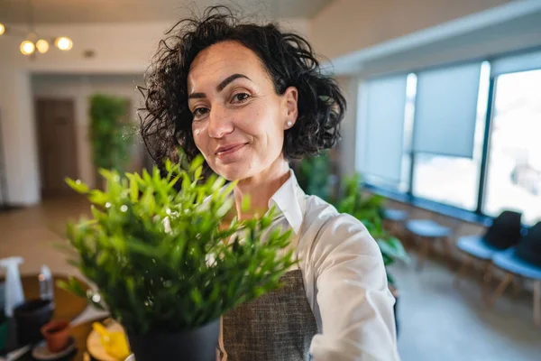 Yetişkin Bir Kadın Elinde Çiçek Bitkileriyle Evde Duruyor Gülümsüyor Tarafta — Stok fotoğraf
