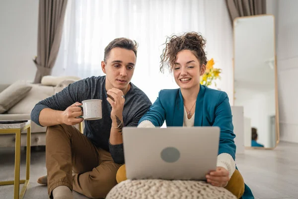 男男女女年轻的高加索人坐在家里的地板上用笔记本电脑和丈夫的家庭观念一起工作快乐地笑着自由职业黑发家庭生活复制空间 — 图库照片