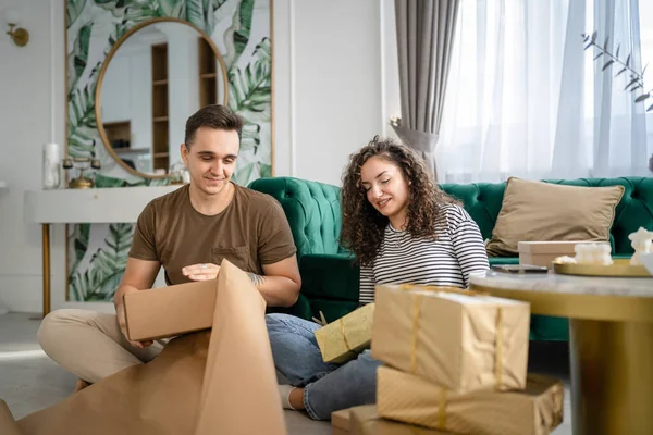 男人和女人用包装纸为朋友准备礼物 男人和女人用包装纸为朋友包装礼物 快乐的微笑在家里拿着礼品盒真实的人抄袭空间 — 图库照片