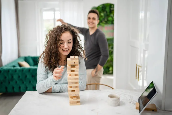 女人和男人快乐的高加索夫妇丈夫和妻子或朋友在家里玩Jenga桌上游戏快乐的微笑闲暇时间和家人在一起时间复制空间真实的人 — 图库照片