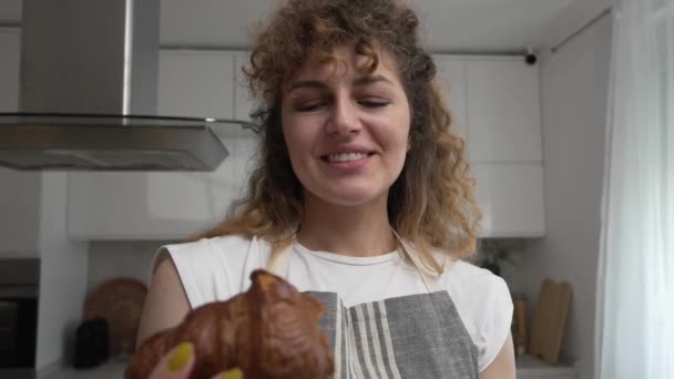 Egy Boldog Fiatal Fehér Kötényt Visel Konyhában Mosoly Enni Croissant — Stock videók