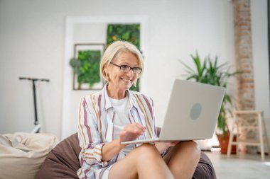 Yetişkin bir kadın Kafkasyalı iş için dizüstü bilgisayar kullanır ya da ofisteki ya da evdeki interneti internette gezer.