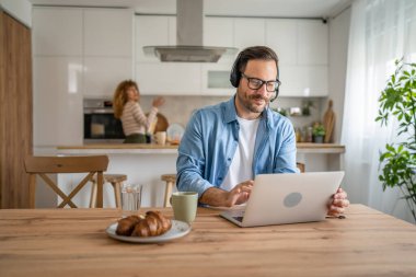Kafkasyalı bir erkek, evinde kulaklıkla bilgisayar destekçisi olarak çalışıyor.