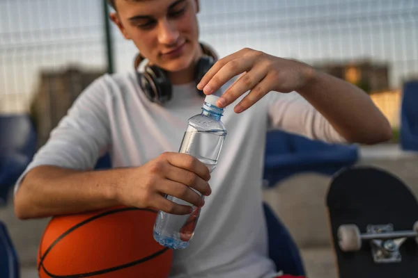 バスケットボールとスポーツをする晴れた日の屋外の未知の慎重な男の開いたプラスチックびんの手の真ん中に近づいて下さい — ストック写真