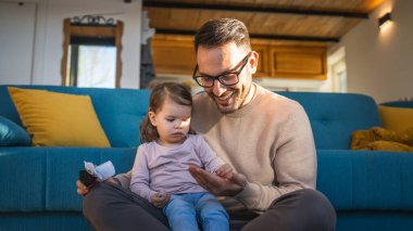 Baba ve kızı evde yerde oynuyorlar olgun yetişkin beyaz adam iki yaşındaki küçük kızıyla oynuyor ebeveynlik yaparak ve aile zamanı konseptini kopyalayarak eğleniyor gerçek insanları taklit ediyor.