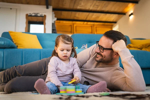 Father and daughter play on the floor at home mature adult caucasian man play with his two years old child toddler girl having fun parenting and bonding family time concept copy space real people