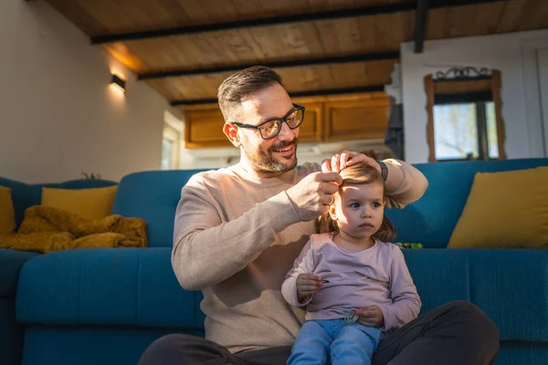 Father and daughter play on the floor at home mature adult caucasian man play with his two years old child toddler girl make doing her hair parenting and bonding family time concept copy space