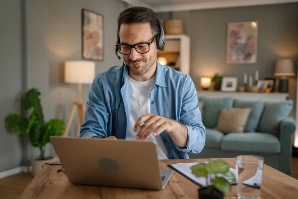 stock image One man caucasian male freelancer work from home with headphones on his head on laptop computer customer support dispatcher happy smile confident