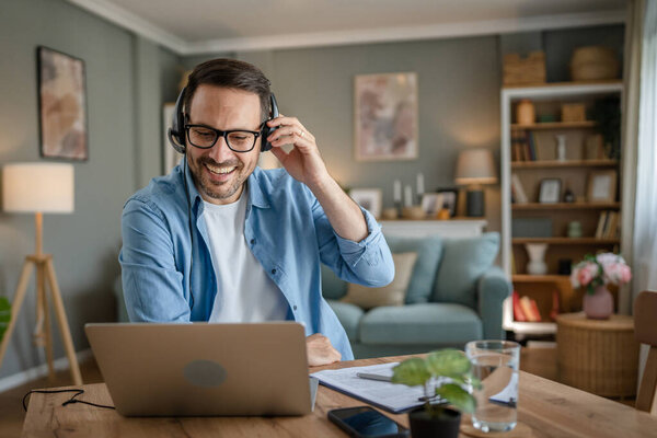 Один человек кавказский мужчина фрилансер работа из дома с наушниками на голове на ноутбуке компьютер поддержки клиентов диспетчер счастливая улыбка уверенно