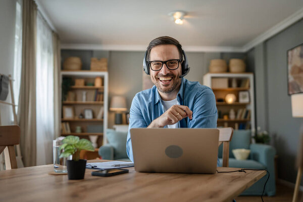 Один человек кавказский мужчина фрилансер работа из дома с наушниками на голове на ноутбуке компьютер поддержки клиентов диспетчер счастливая улыбка уверенно