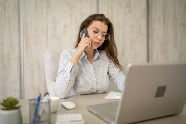 Bir kadın beyaz girişimci iş kadını ya da sekreteri masasında oturmuş telefon konuşması yapacağından endişe ediyor.