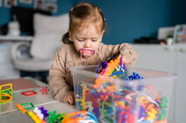 Bir çocuk, küçük beyaz kız, meme ucu emziği olan, evde tek başına oynayan, çocukluk dönemi konsepti fotokopi alanı.