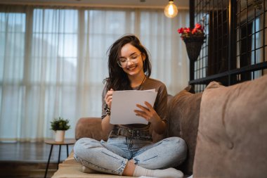 Yetişkin bir kadın, beyaz bir kız öğrenci, evinde kanepede oturup gazete okuyor. Sınav çalışmalarını tek başına hazırlıyor. Gerçek insanların eğitim konseptini taklit ediyor.