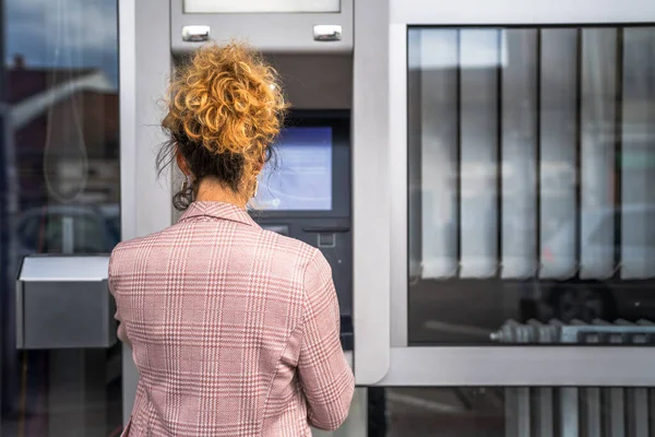 Kadın kredi kartı kullanıyor ve ATM 'den para çekiyor.