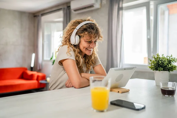Kıvırcık Saçlı Beyaz Bir Kadın Evde Oturup Dijital Tablet Kulaklık — Stok fotoğraf