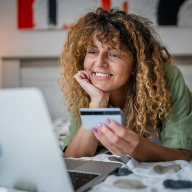 Evde yetişkin bir kadın online alışveriş için kredi kartı ya da banka kartı kullanıyor. İnternet mağazaları indirimli indirimli indirimli ürünler alıyor. Gerçek insanlar yer bilgisayarlarını kopyalıyor.