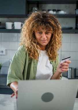 Evde yetişkin bir kadın online alışveriş için kredi kartı ya da banka kartı kullanıyor. İnternet mağazaları indirimli indirimli indirimli ürünler alıyor. Gerçek insanlar yer bilgisayarlarını kopyalıyor.