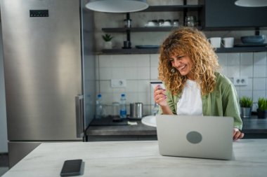 Evde yetişkin bir kadın online alışveriş için kredi kartı ya da banka kartı kullanıyor. İnternet mağazaları indirimli indirimli indirimli ürünler alıyor. Gerçek insanlar yer bilgisayarlarını kopyalıyor.