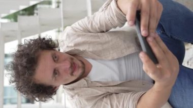 Beyaz bir adam dışarıda oturur, mutlu bir şekilde gülümser, video oyunları oynar, eğlenir, cep telefonu kullanır, akıllı telefon kullanır, internetteki yetişkin erkeklerin yavaş çekimde eğlenmesini sağlarım.