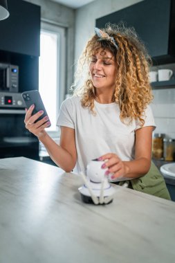 Yetişkin bir Kafkasyalı kadın güvenlik kamerası uygulamasını ayarlayıp hazırlıyor ve akıllı telefonu kullanarak kopyalama alanı kuruyor.