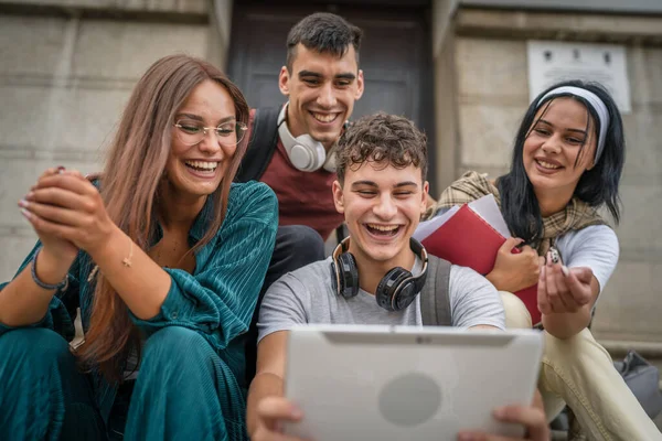 一群高加索青少年朋友坐在学校或大学前 举行数字平板电脑观看视频电影 或通过视频上网浏览社交网络真实的人 — 图库照片