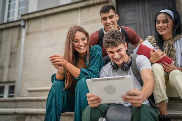 慎重な十代の友人のグループは 学校や大学の前に座ってデジタルタブレットの視聴ビデオ映画を保持したり ソーシャルネットワークの本当の人々のためにオンラインビデオ通話ブラウズインターネットを持っています — ストック写真
