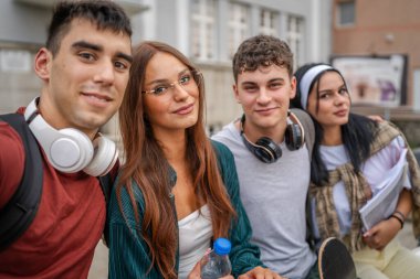 Bir grup genç öğrenci, üniversitenin erkek ve bayan arkadaşlarının önünde selfie çekiyorlar kampüsün önünde beyaz erkek ve kadın ergenler sınıfın konseptine dönmesini bekliyorlar.