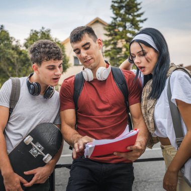 Bir grup ergen öğrenci, üniversitenin önünde ders çalışırlar. Erkek ve kadın arkadaşlar, beyaz erkek ve kadın gençler kampüsün önünde sınava hazırlanırlar. Okuma konseptini yeniden öğrenirler.