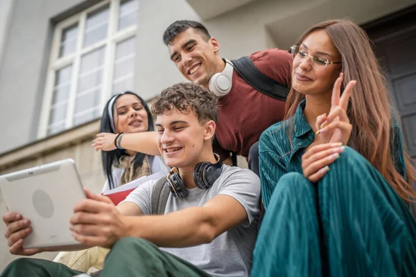 一群高加索青少年朋友坐在学校或大学前面 在社交网络上在线观看数字平板电脑流 或者在网上观看视频 — 图库照片