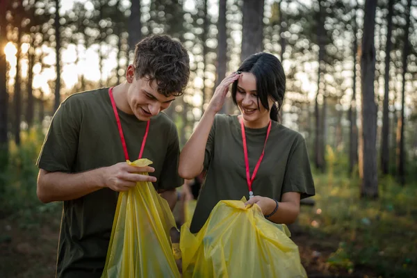 夫妇或青少年朋友一男一女高加索男子从森林中捡垃圾塑料瓶和废纸清洁自然阳光明媚的白天环境保护生态概念 — 图库照片