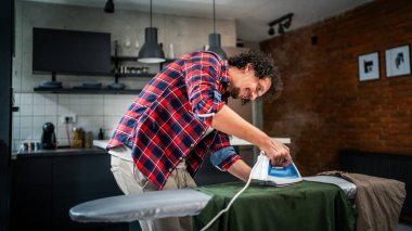 Evde ütü yapan bir adam, ev işlerinde gömleğini ütülüyor ev işlerinde ütü yapıyor 30 'lu yaşlarda evde tek başına yaşayan yetişkin bir erkek, fotokopi odasında çalışıyor.