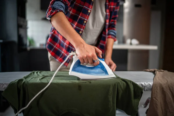 一位男人在家里熨烫衣服时 把熨斗放在衬衫上放在家务活的概念上30多岁的男人一个人住在公寓里做家务活 — 图库照片