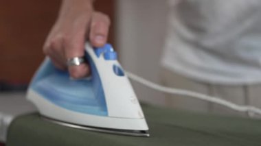 Evde ütü yapan bir adam, ev işlerinde gömleğini ütülüyor ev işlerinde ütü yapıyor 30 'lu yaşlarda evde tek başına ev işi yapan yetişkin bir erkek.