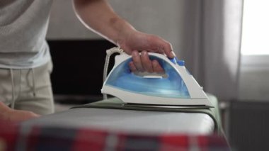 Evde ütü yapan bir adam, ev işlerinde gömleğini ütülüyor ev işlerinde ütü yapıyor 30 'lu yaşlarda evde tek başına ev işi yapan yetişkin bir erkek.