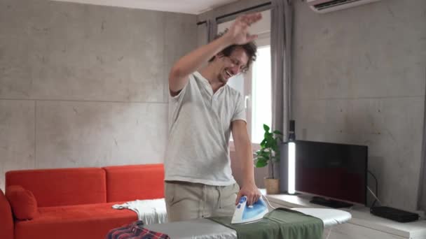 Ένας Άνδρας Σιδερώνει Ρούχα Στο Σπίτι Κρατάει Σίδερο Στο Πουκάμισο — Αρχείο Βίντεο