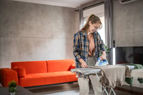 1人の若い女性 十代の学生 アイロン掛けの服 家で初めてシャツの上にアイロンを保持 家事のコピースペースをするだけでアパートに住んでいる女性のコンセプトをチェア — ストック写真