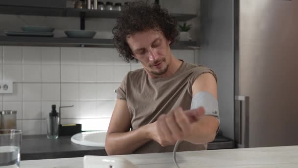 一位男性白种人坐在桌旁检查血压 以衡量家庭保健的真实概念 — 图库视频影像