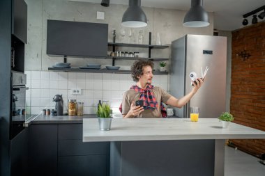 Beyaz adam güvenlik kamerası ve cep telefonunu elinde tutuyor. Kurulumu sağlayan bir uygulama yüklemeye ve güvenlik kamerası izleme sistemi kurmaya çalışıyor.