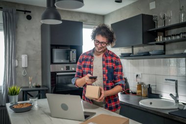 Beyaz bir adam online alışveriş ürünlerinin nakliye detaylarını kontrol etmek için akıllı telefon kullanıyor. Akıllı telefon uygulaması başvurusunu kontrol edin. Çevrimiçi detaylar mutlu bir gülümseme.