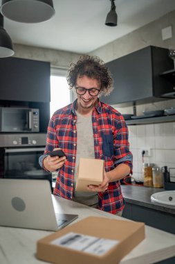 Beyaz bir adam online alışveriş ürünlerinin nakliye detaylarını kontrol etmek için akıllı telefon kullanıyor. Akıllı telefon uygulaması başvurusunu kontrol edin. Çevrimiçi detaylar mutlu bir gülümseme.